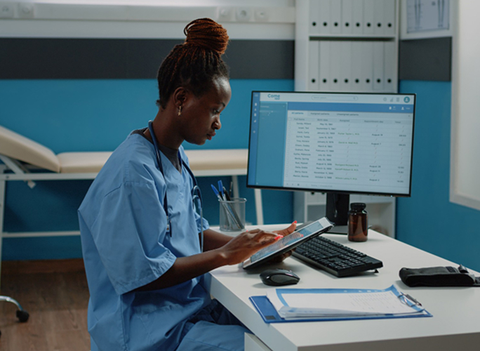A nurse at a workstation reviewing a health record on screen