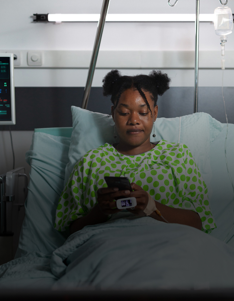 A patient in a hospital bed reading her health records on her phone